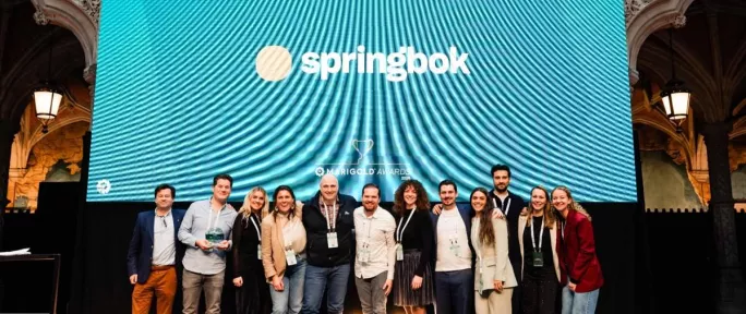 Marigold - A group of people from Springbok agency standing on stage smiling in front of a large screen that reads “Award Winner - Springbok” at the Marigold Awards event. The background shows an ornate venue with gothic-style architecture.